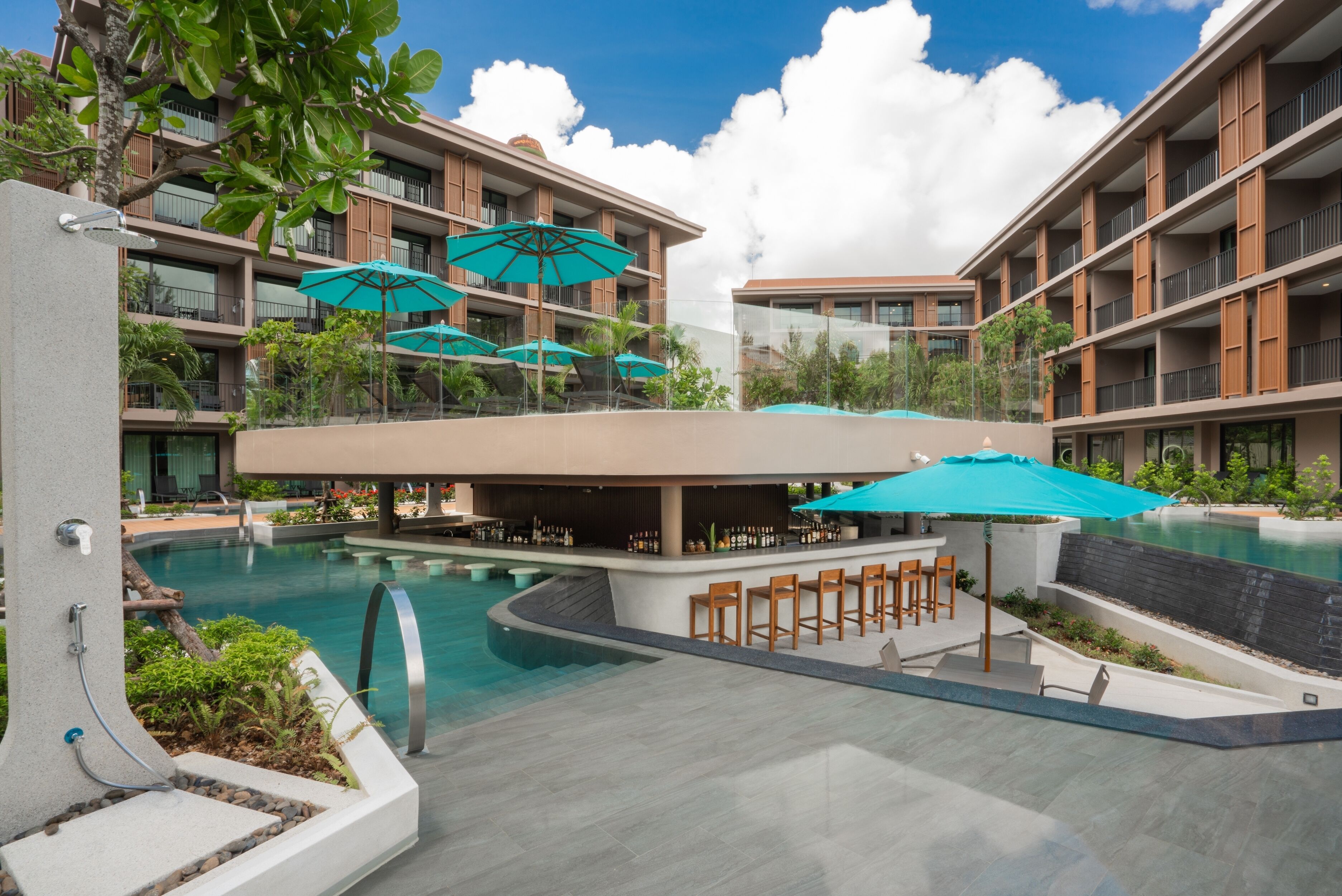 Un hotel moderno con piscina, zona de estar exterior y varios balcones.