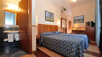 Une chambre d’hôtel avec un lit, une salle de bain avec un lavabo et deux tableaux accrochés aux murs.