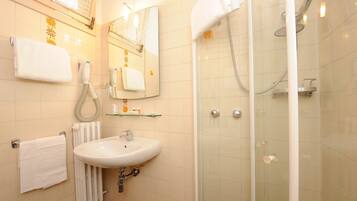 Une salle de bain équipée d’un lavabo, d’un miroir, d’un porte-serviettes et d’une douche à parois en verre.