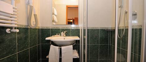 Un baño con lavamanos, espejo, toallero y ducha.