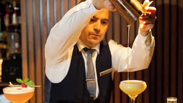 A bartender pouring a drink into a martini glass.
