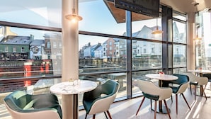 A modern interior with large windows, round tables, and green chairs.