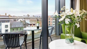 A balcony with a table, chairs, and a vase of flowers.