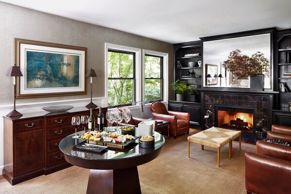A dining area with a round table set for a meal, a fireplace, leather seating, and a bookshelf. - Gaige House (Glen Ellen)