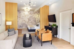 A modern living room with a sofa, armchairs, a coffee table, a TV, and a decorative wall.