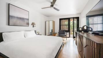 A modern hotel room with a large bed, a ceiling fan, a TV, and a view of the outdoors.