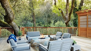 A deck with outdoor furniture, a fire pit, and a view of a forested area. - Gaige House  (Glen Ellen)