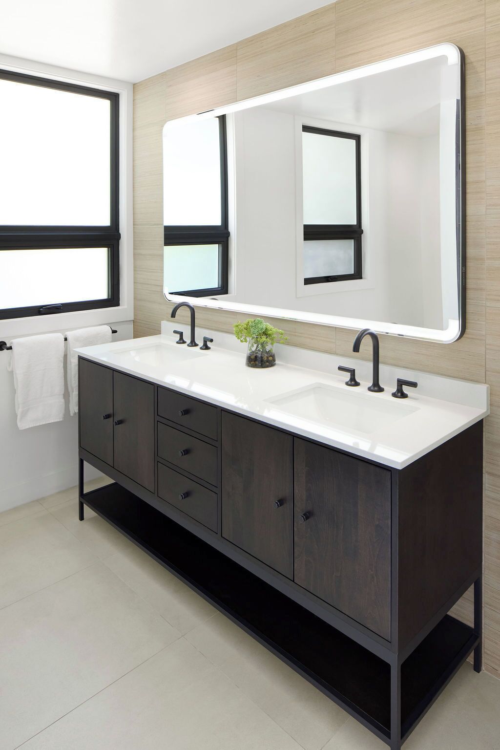 A modern bathroom with a dark wood vanity, two sinks, and a large mirror.