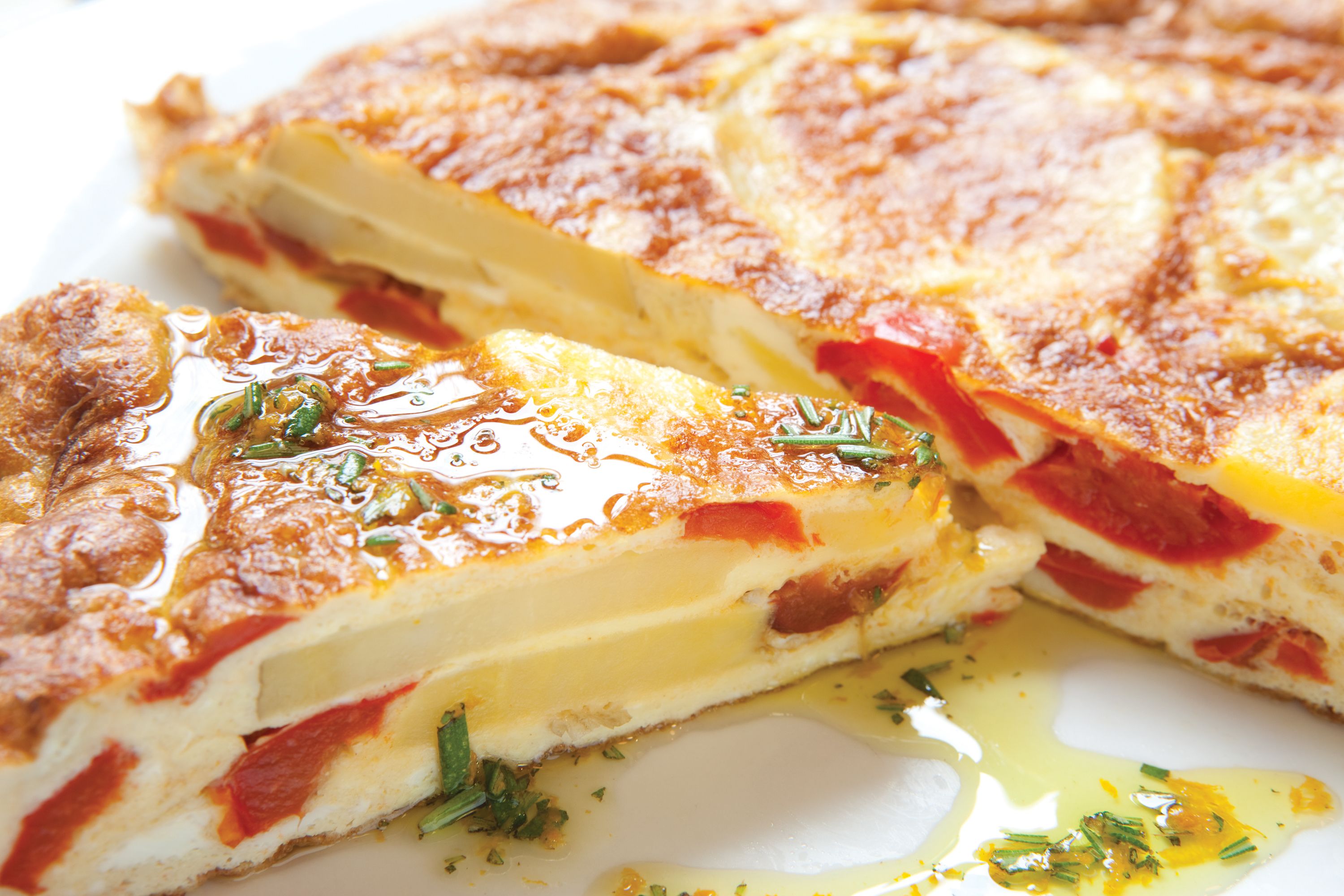A close-up of a savory dish with layers of cheese and tomato, garnished with herbs.