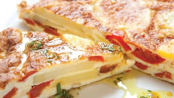 A close-up of a savory dish with layers of cheese and tomato, garnished with herbs.