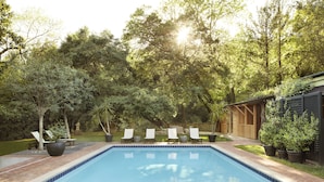 A swimming pool with lounge chairs, surrounded by greenery and a wooden deck. - Gaige House  (Glen Ellen)