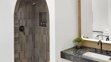 Un bagno moderno con una finestra a lucernario, un lavabo freestanding e una zona doccia con parete rivestita in piastrelle.
