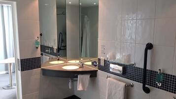 A modern bathroom with two sinks, a large mirror, and a black grab bar.