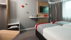 A hotel room with two beds, a TV mounted on the wall, a small table, and a shelf with a kettle and cups. - Holiday Inn Express Leeds City Centre Armouries by IHG (Leeds)