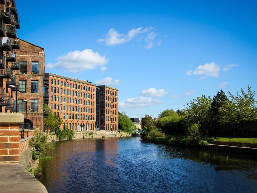 A river with buildings on one side and greenery on the other.