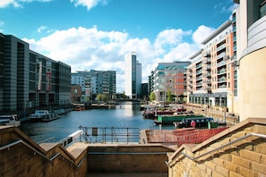 A riverside view with modern buildings, a bridge, and boats. - Holiday Inn Express Leeds City Centre Armouries by IHG (Leeds)