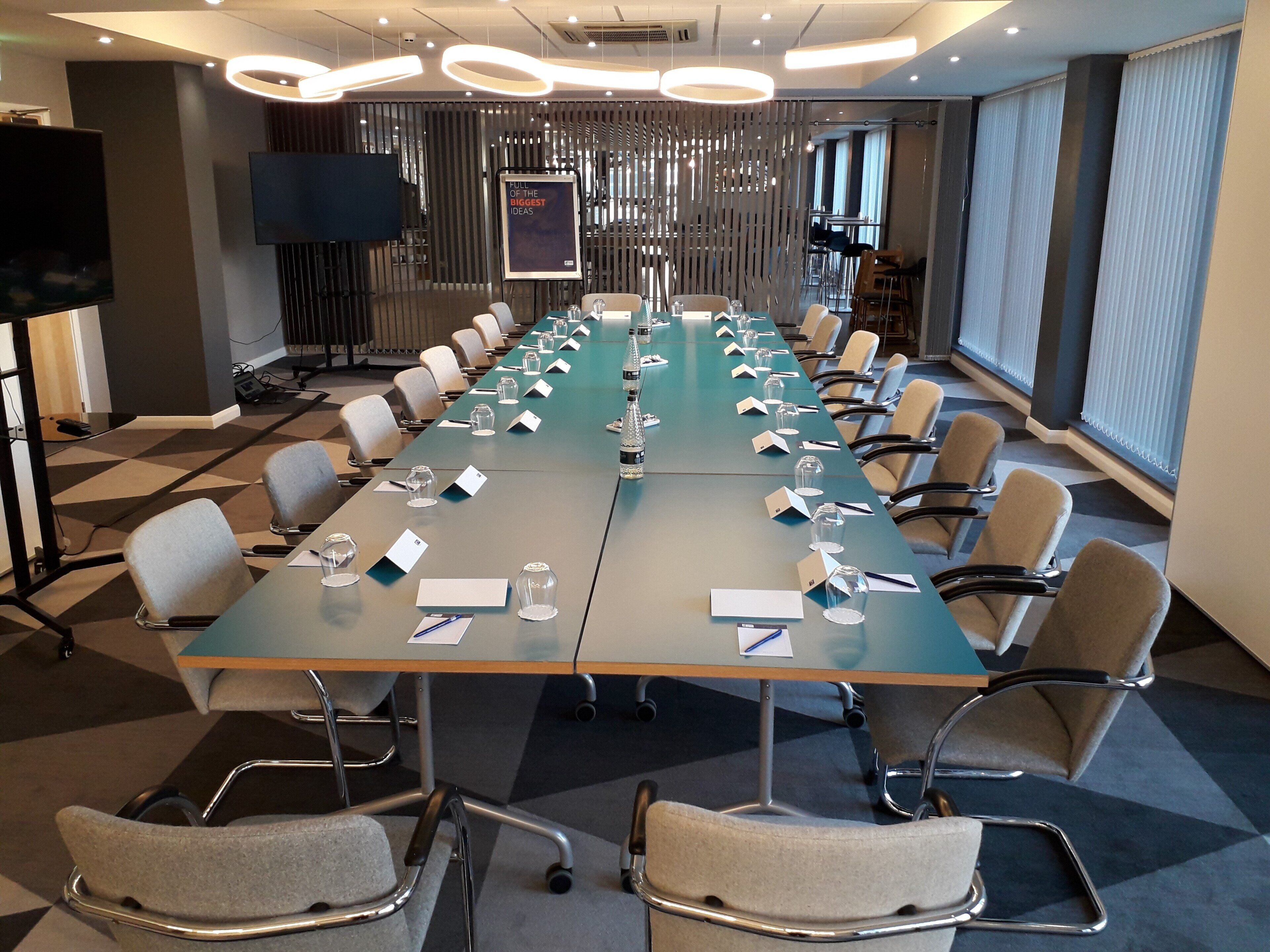 A conference room with a long table, chairs, nameplates, and glassware.