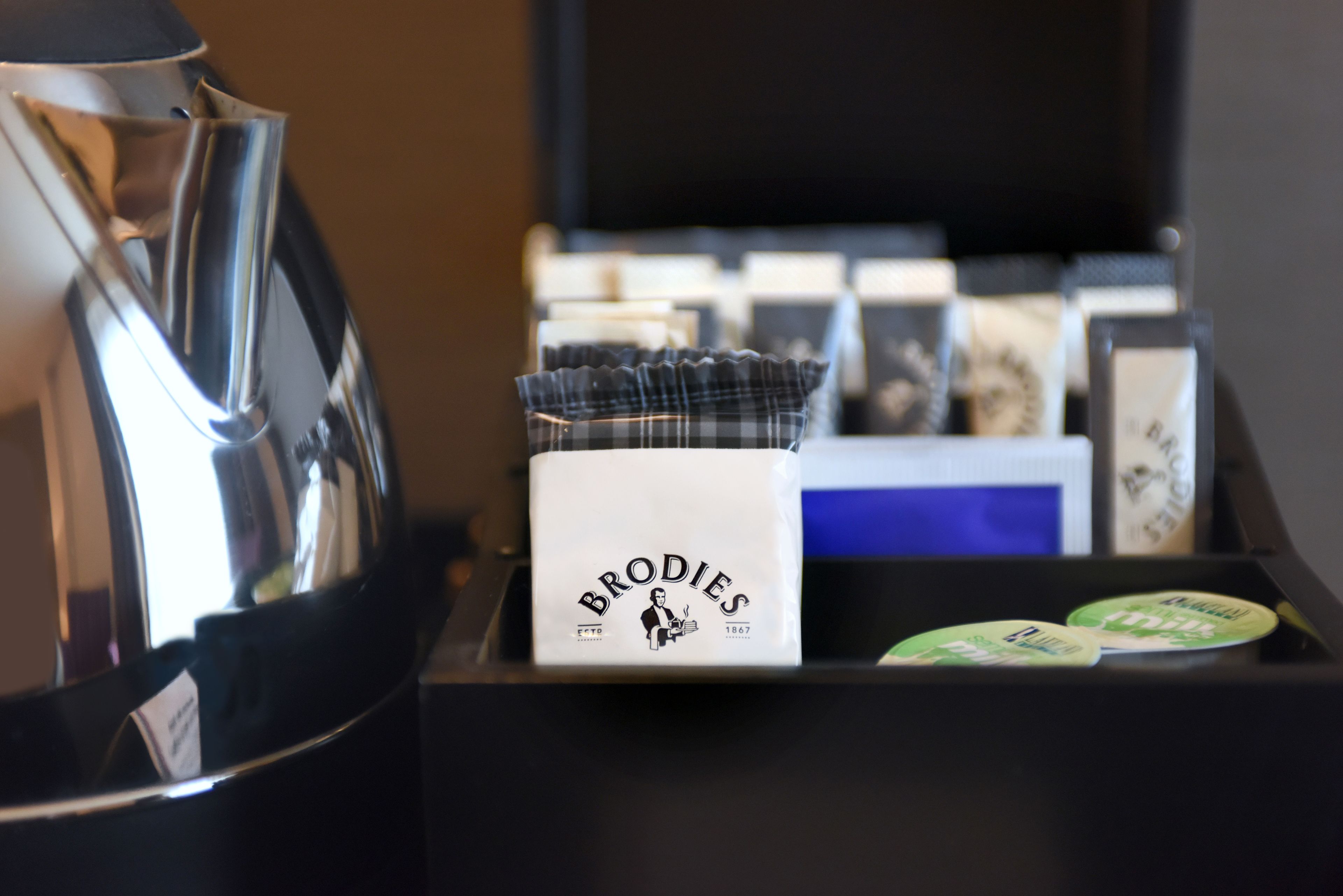 Una cafetera y una caja con el rótulo 'Brodie's' y un logotipo antiguo.