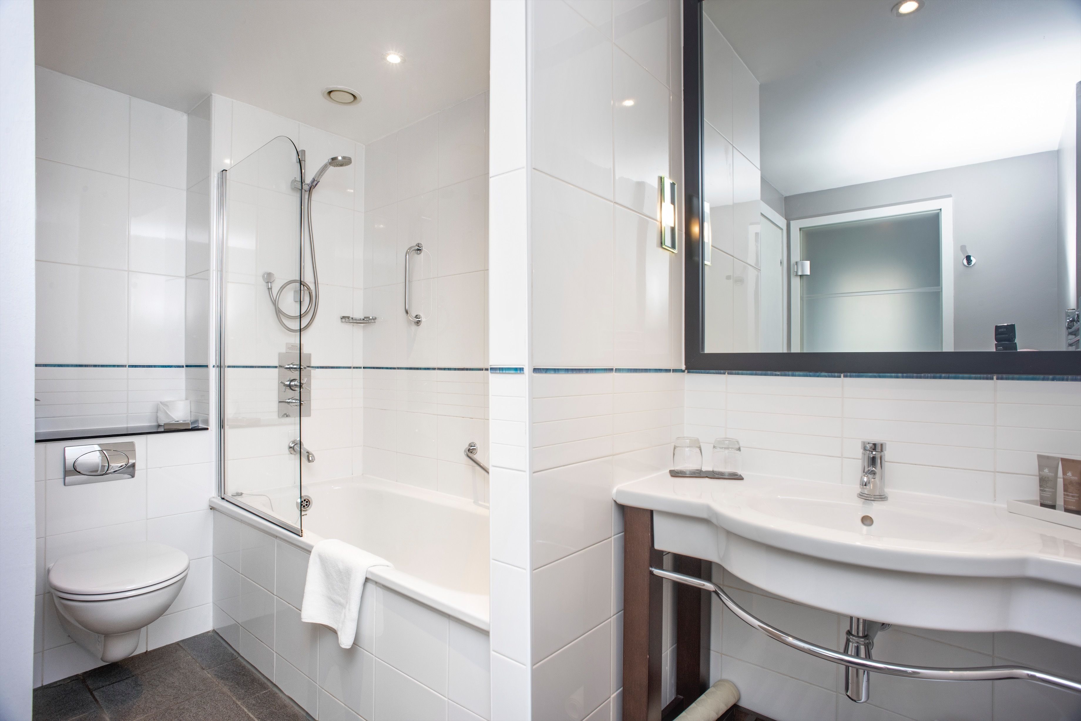 A modern bathroom with a glass-enclosed shower, a white sink with a mirror, and a toilet.