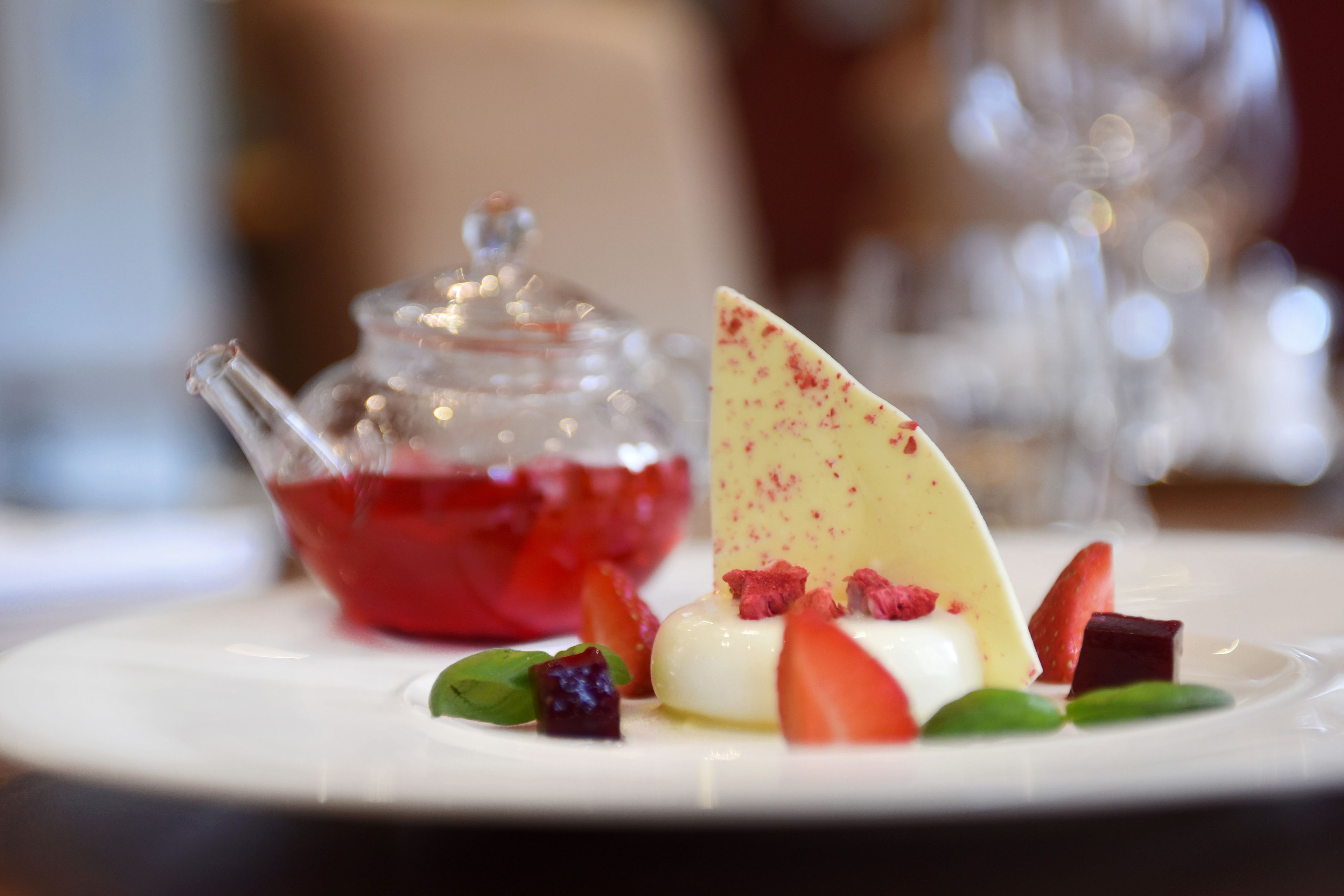 A dessert plate with various fruits and a glass teapot.