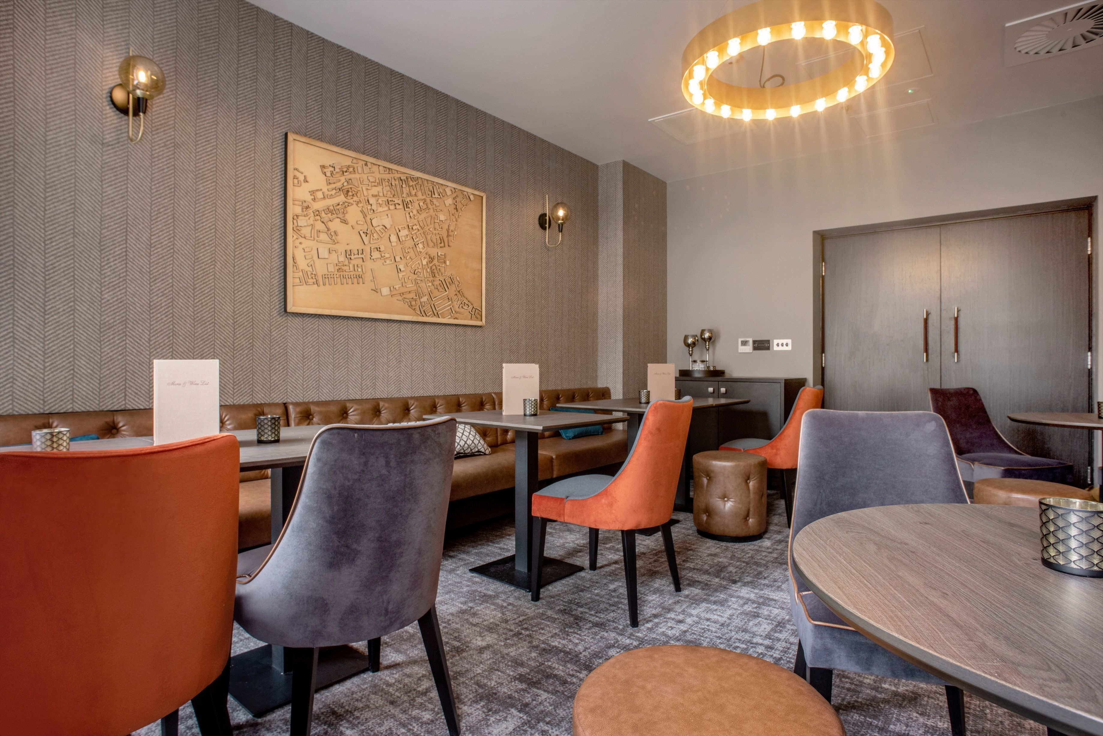 A modern restaurant with a high ceiling, a large map on the wall, and a variety of seating options including booths and tables.