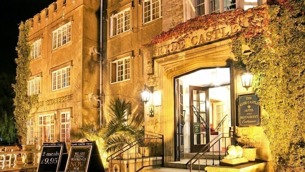 A historic building with a stone facade, a prominent entrance with steps, and signage indicating it is a hotel and restaurant.