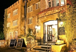 A historic building with a stone facade, a prominent entrance with steps, and signage indicating it is a hotel and restaurant.