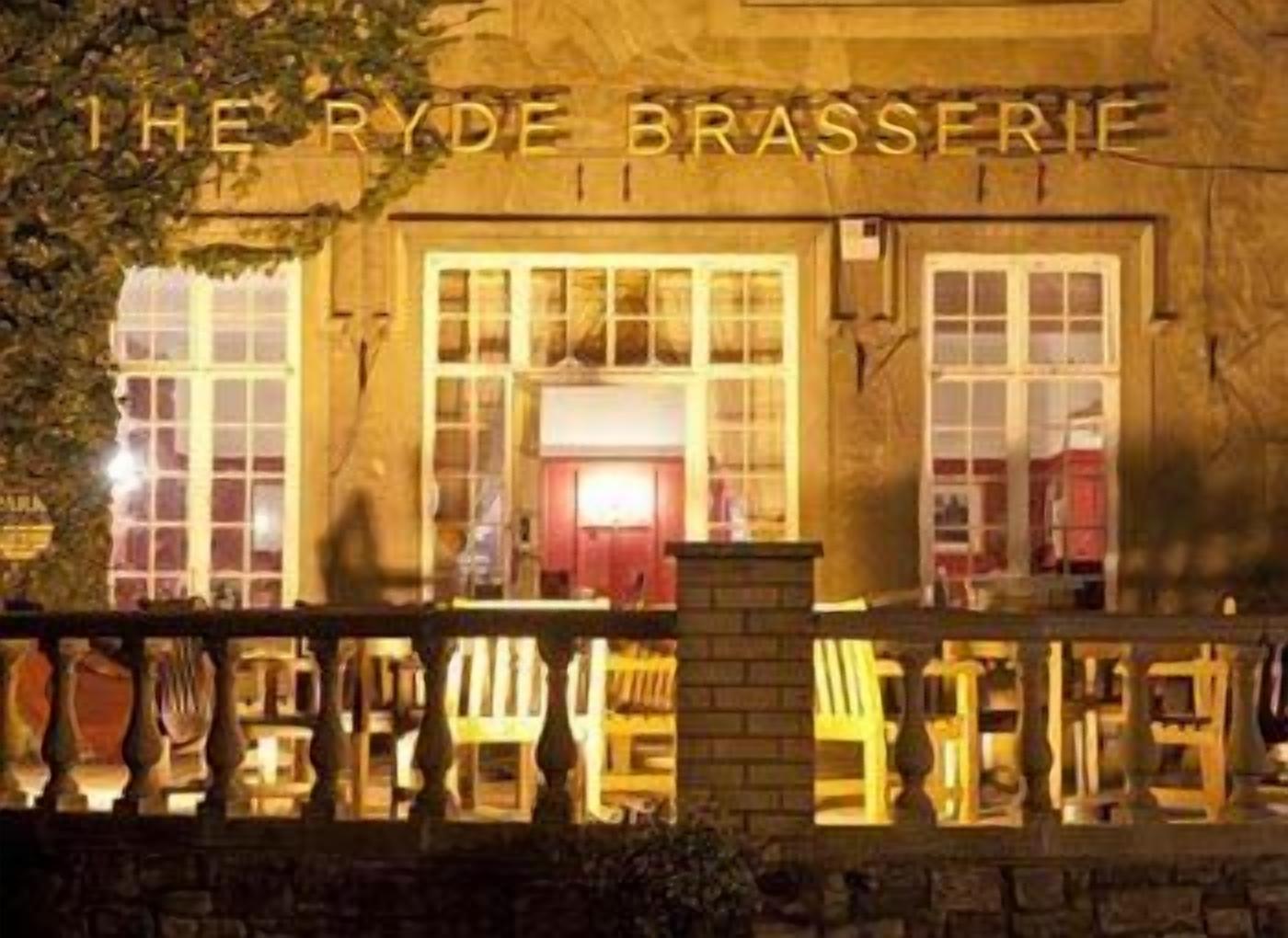 A building with a sign reading "THE RYDE BRASSERIE" at night.