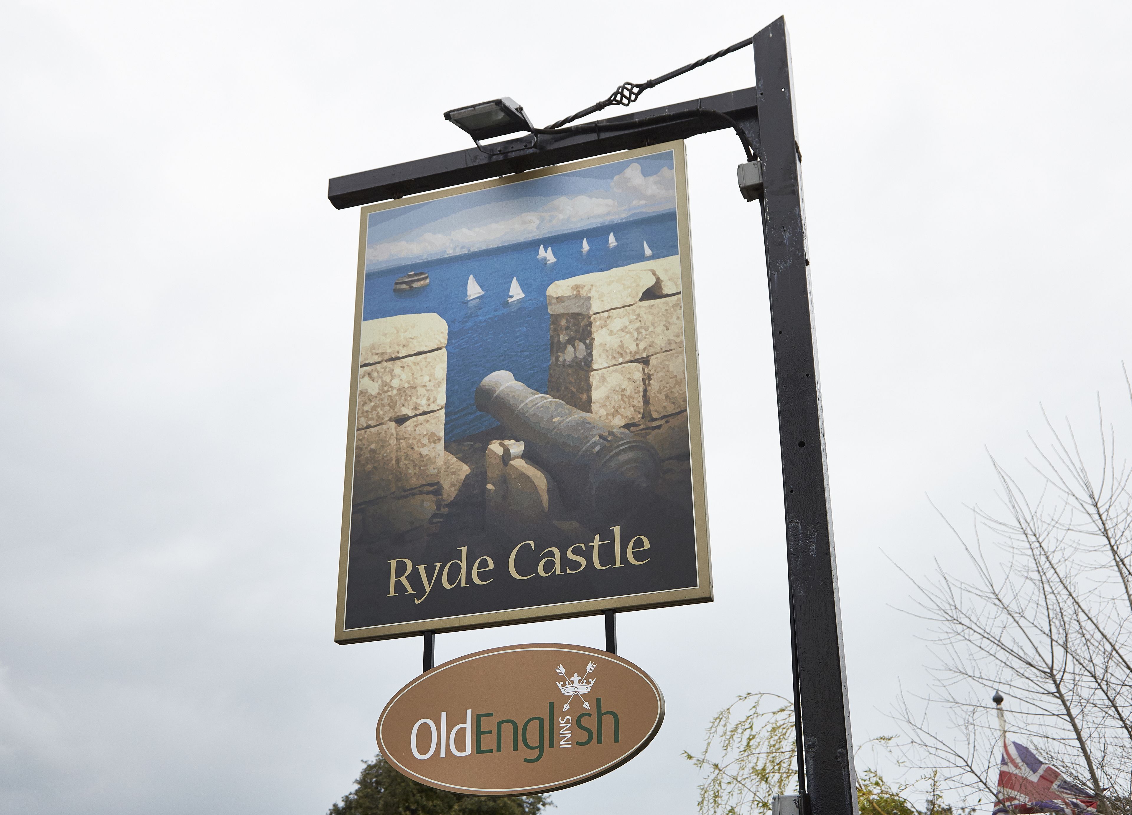 A sign for Ryde Castle pub with a coastal scene and a flag.