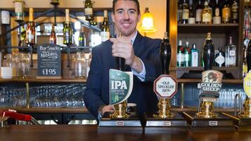 A bar with a person holding a beer tap labeled "IPA" and other taps labeled "Old Speckled Hen" and "Golden Sheep."