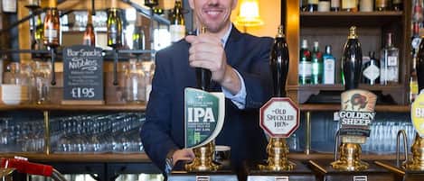 A bar with a person holding a beer tap labeled "IPA" and other taps labeled "Old Speckled Hen" and "Golden Sheep."