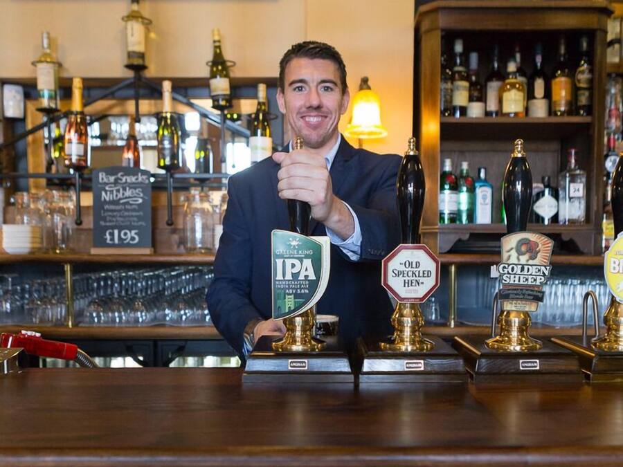 A bar with a person holding a beer tap labeled "IPA" and other taps labeled "Old Speckled Hen" and "Golden Sheep."