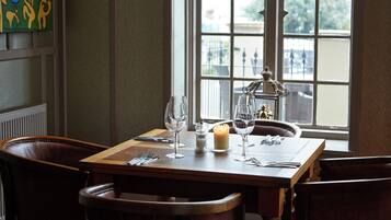 A dining table set with wine glasses, a candle, and cutlery.