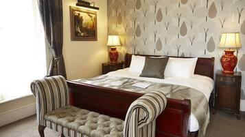 A neatly made bed with a striped headboard, a bench at the foot of the bed, and two lamps on nightstands.