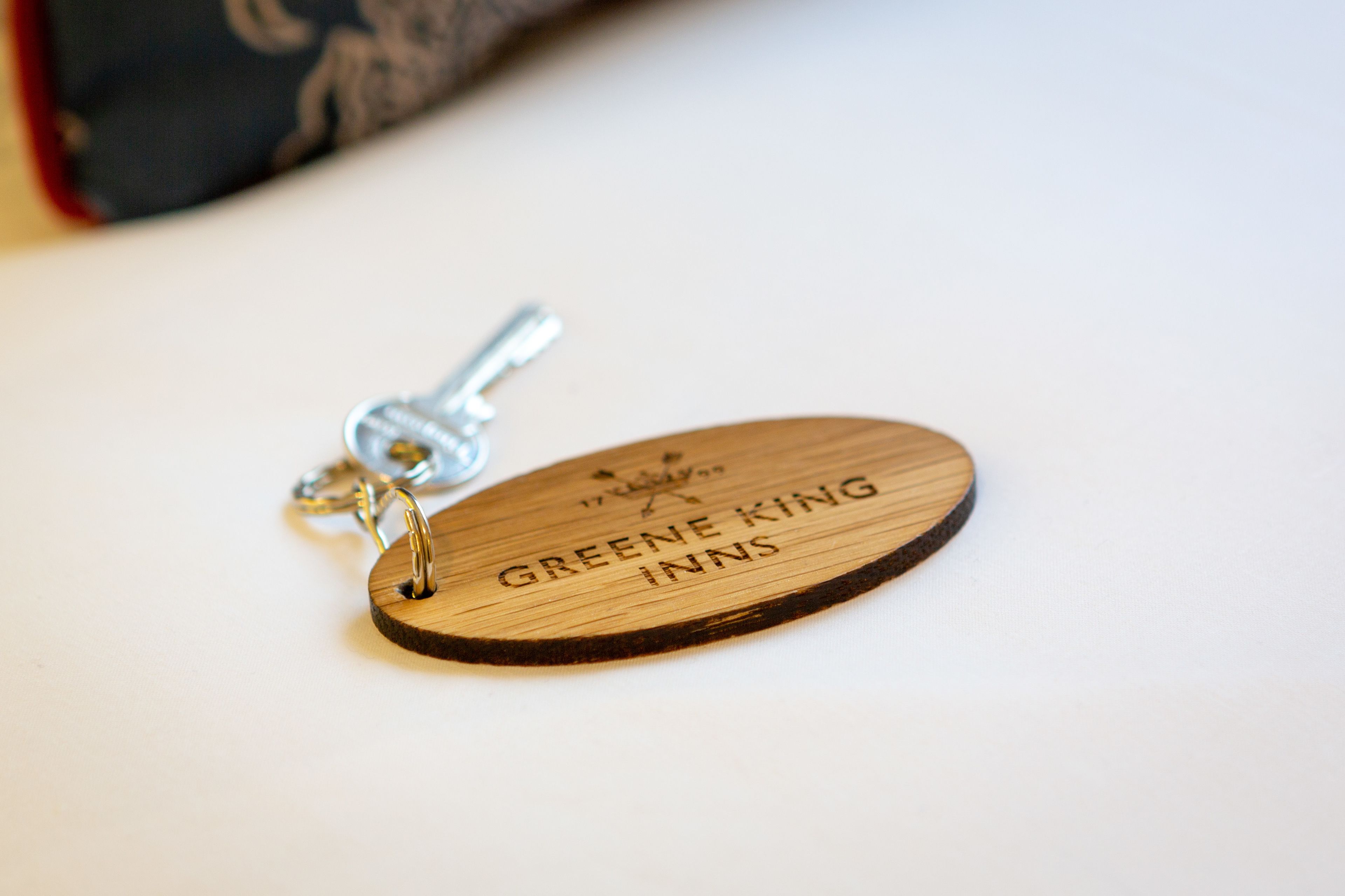 A wooden keychain with the text "Greene King Inns" engraved on it.