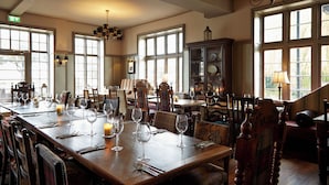 A dining area with wooden tables, chairs, and a chandelier.