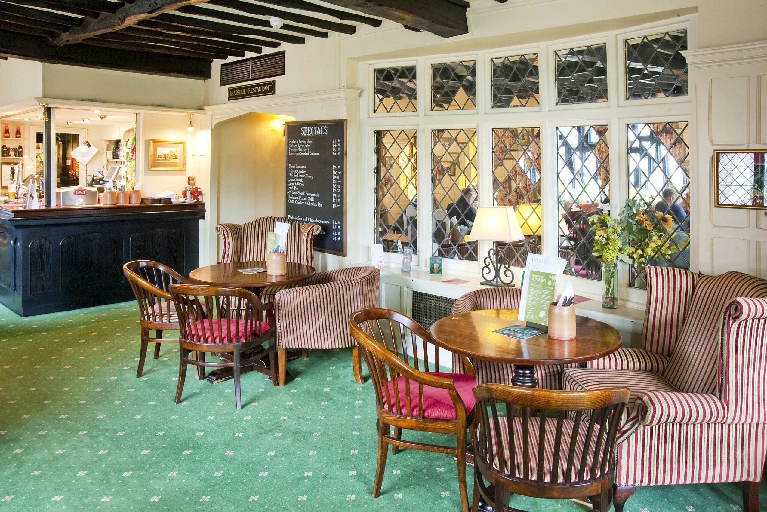A cozy restaurant interior with striped upholstered chairs, a wooden table, and a menu board.