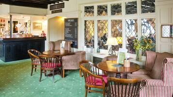 A cozy restaurant interior with striped upholstered chairs, a wooden table, and a menu board.