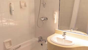 Et badeværelse med badekar, vask, toilet og bruser.