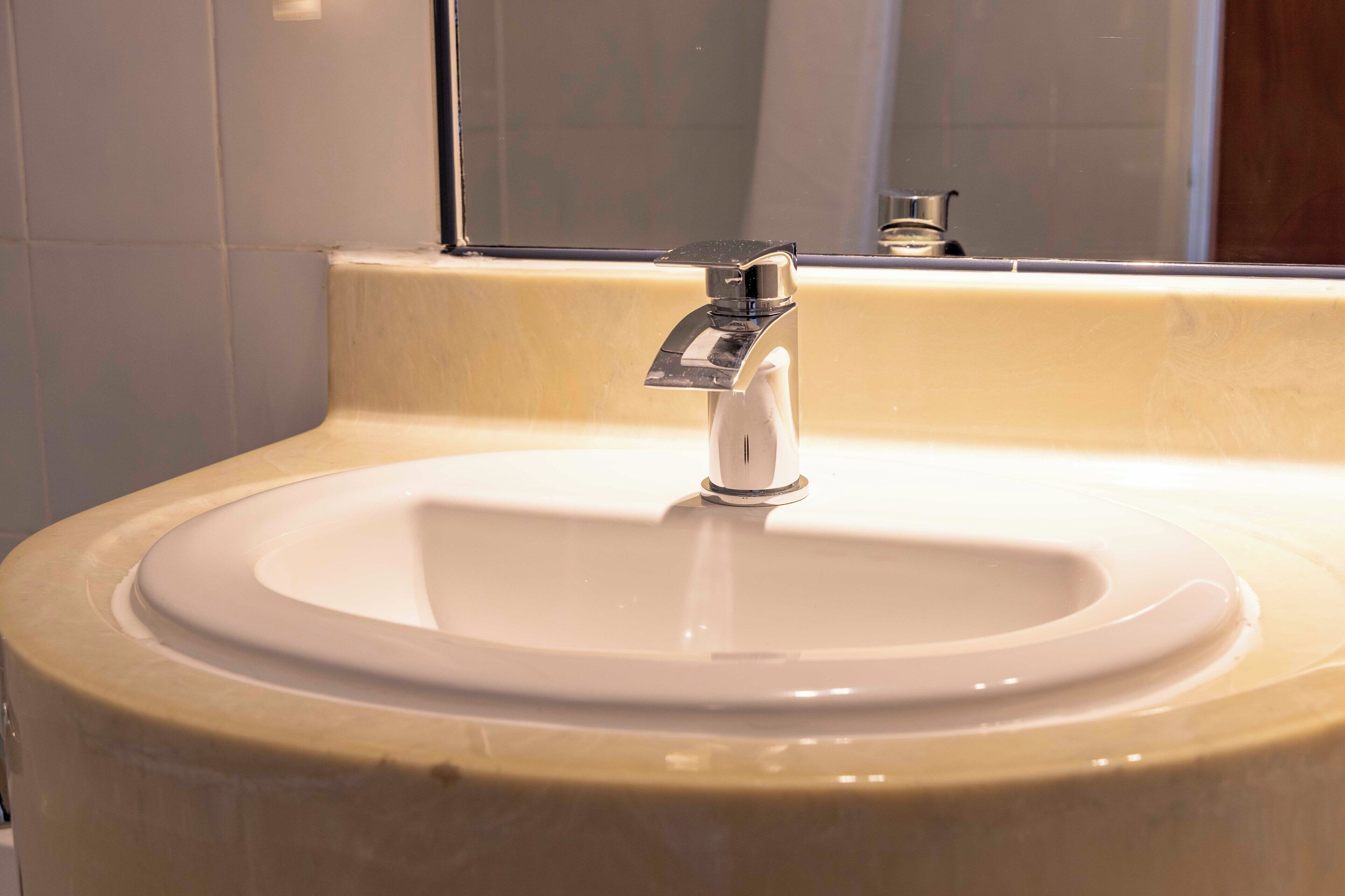 Un lavabo con rubinetto cromato e uno specchio sopra.