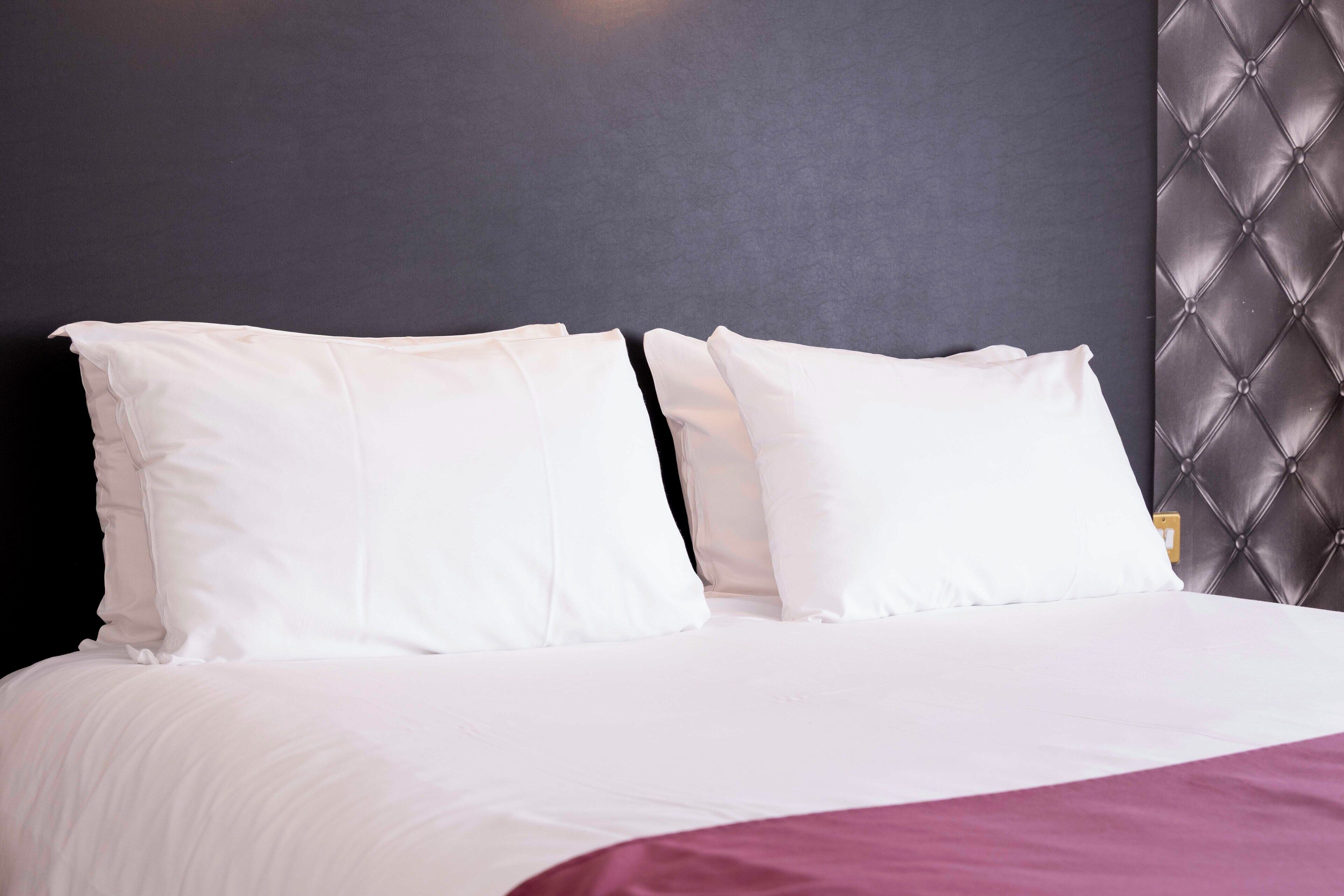 A bed with white bedding and a dark headboard.