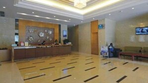 Un hall d’hôtel avec un comptoir d’accueil, un lustre et un écran de télévision.