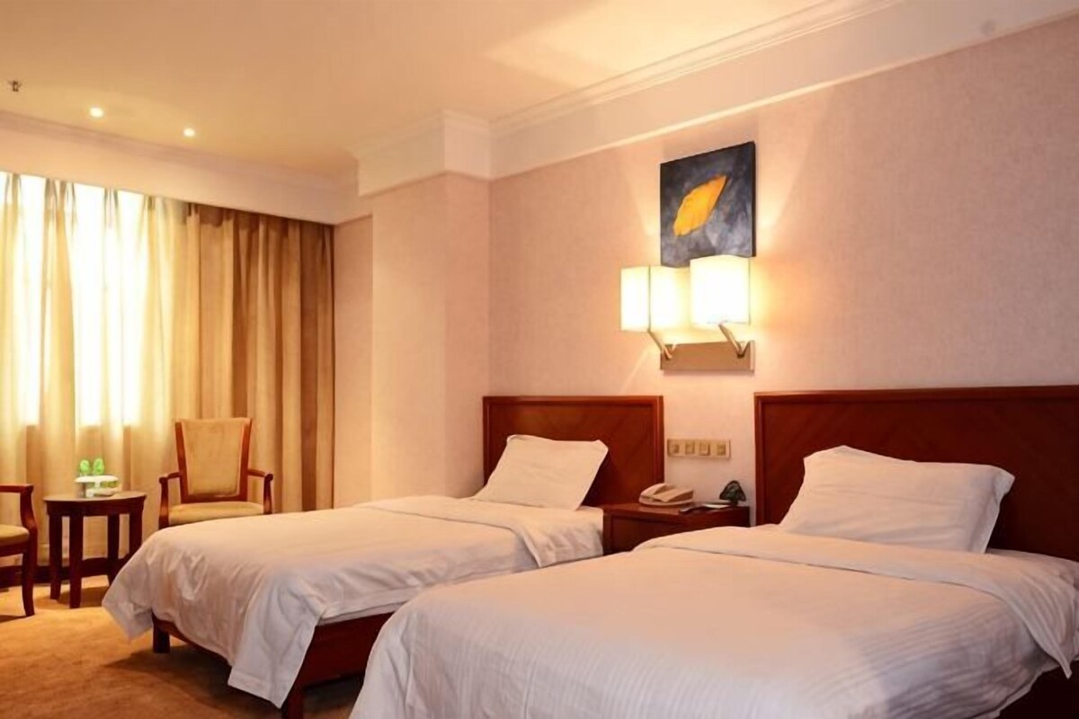 Une chambre d’hôtel avec deux lits, un bureau, une chaise et un tableau au mur.