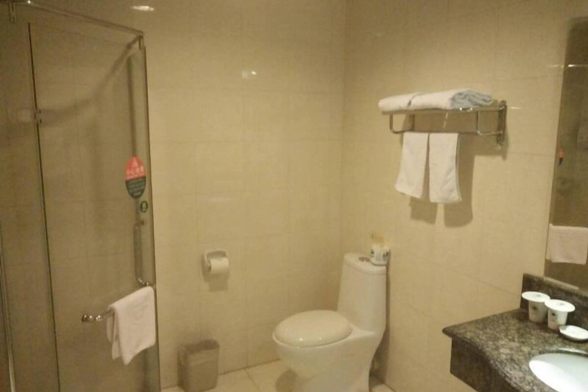 Un baño con inodoro, lavamanos, cabina de ducha de vidrio y toallero con toallas.