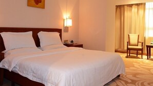 Une chambre d’hôtel avec un grand lit, une table de chevet, une lampe, une chaise et un tableau au mur.