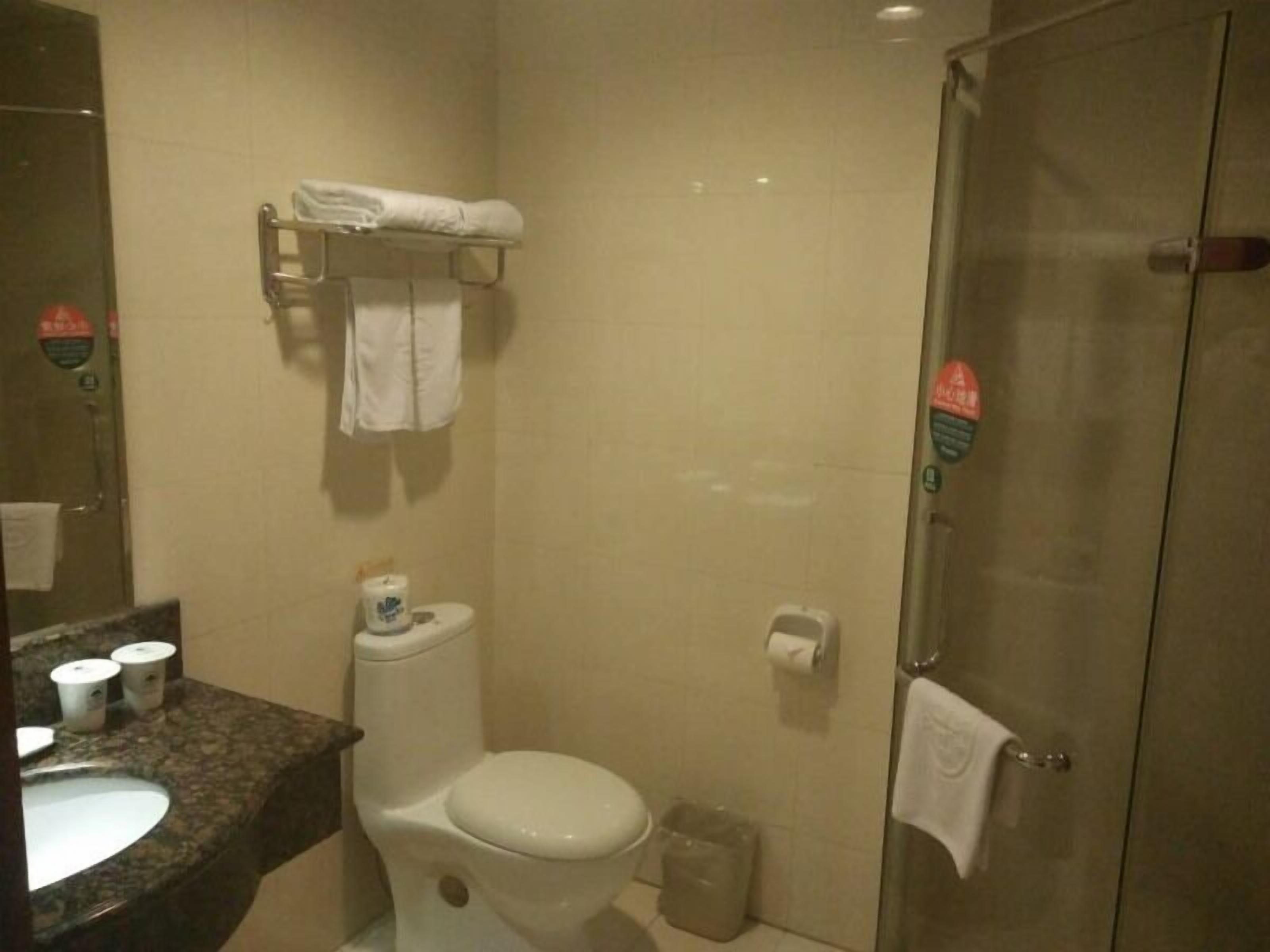A bathroom with a toilet, sink, and a glass shower door.