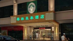 L’entrée d’un hôtel, avec une enseigne indiquant « Green Tree Inn » et une autre pour un restaurant.