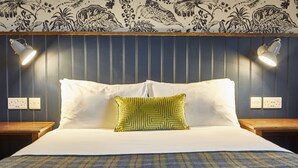 A neatly made bed with white linens and a green patterned pillow, flanked by two bedside tables with lamps. - Swan Hotel by Greene King Inns (Alton)
