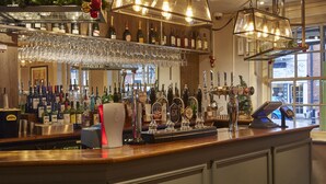 A bar area with a variety of bottles, glasses, and a cash register. - Swan Hotel by Greene King Inns (Alton)