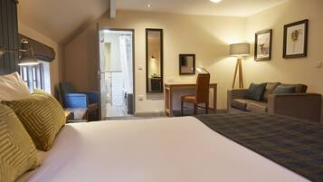 A hotel room with a bed, a desk, a chair, a sofa, a lamp, and a mirror.